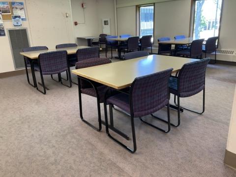 Open space with ugly pink carpet, 4 large tables, 4 purple chairs at each table, large windows
