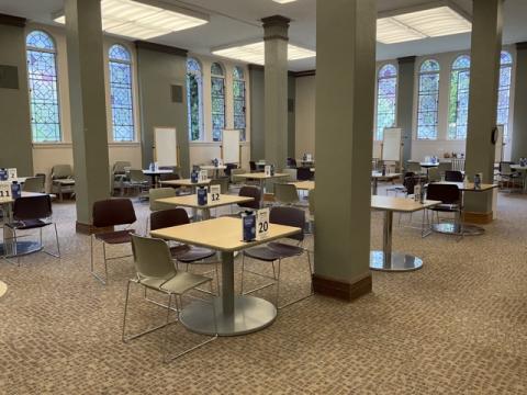 tables and chairs scattered in a large open space with tall ceilings and tall rounded stained glass windows