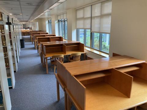 A long, narrow space with windows and carrels against the right wall. There are bookcases on the lefthand side.