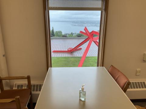 A long table against a window. Outside, the overlook near WWU's Union and the statue therein is visible. Bellingham bay is in the distance.