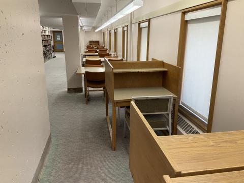 Long narrow space, confined by columns on the left side. Carrols in foreground, long tables along right wall. Bookshelves on the back left.