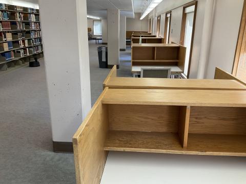 An open space, divided by three columns. Carrels, back-to-back, line the right wall and extend to the back of the room. Bookstacks on the far left.