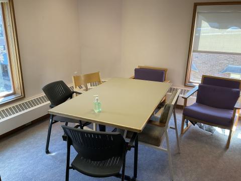 A small room with a long table surrounded by chairs. A single window on the left and back wall.