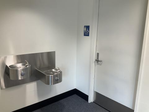 A closed door to a women's restroom, water fountains on adjacent wall to the left.