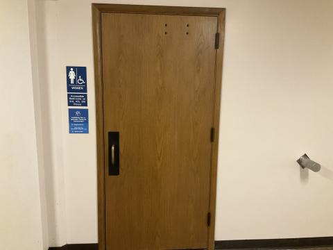 Closed door to women's restroom. Signage denoting gender to left of door.
