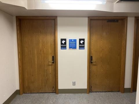 Two closed wood doors, gender neutral signs between the doors